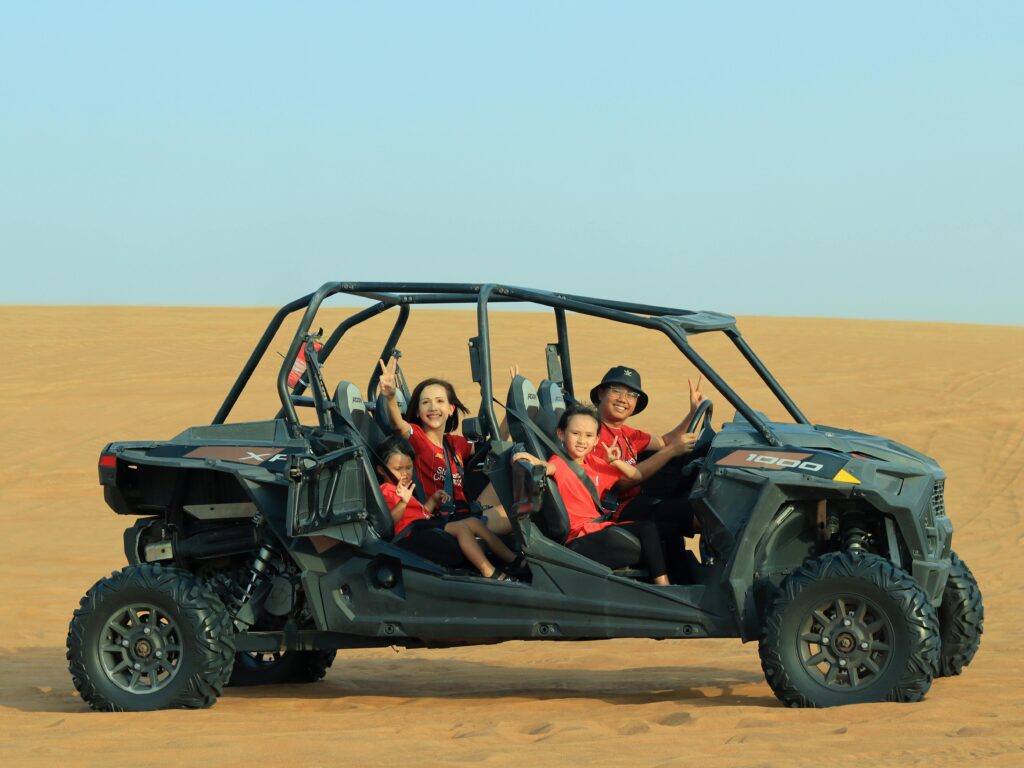 “Smiling kids riding a camel during a family desert safari in UAE