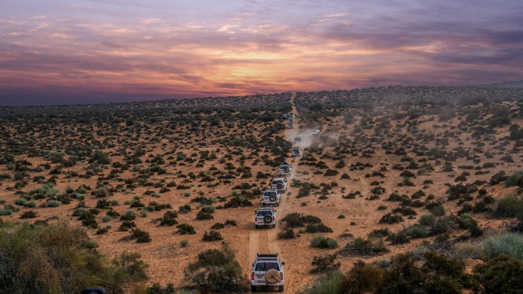 Tourists enjoying thrilling dune bashing in a 4x4 Land Cruiser during evening desert safari in Dubai.